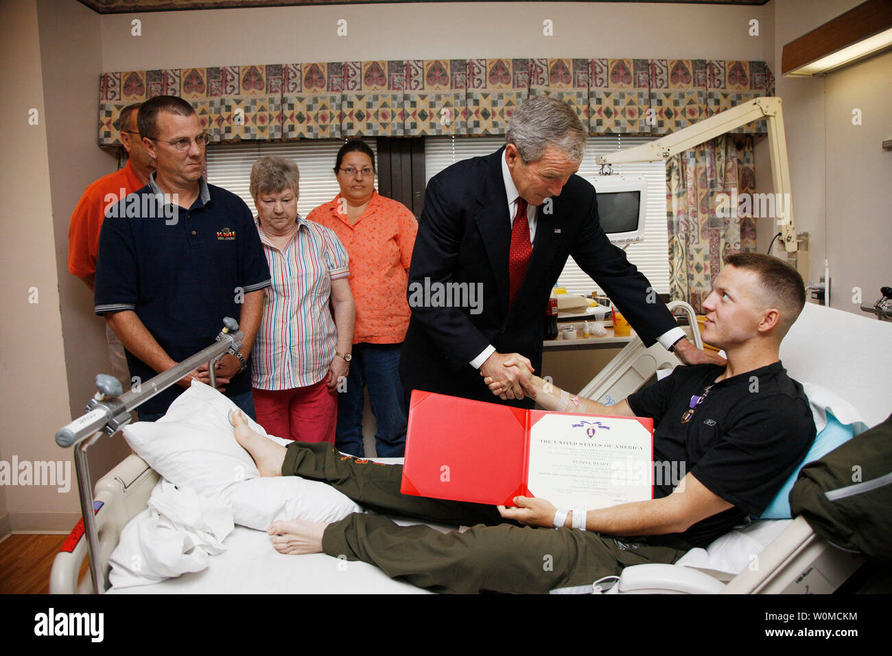 U.S. President George W. Bush shakes hands with with  U.S. Marine Corps Pfc. Charles Cozart of Arizona City, Arizona, after awarding him a Purple Heart medal at the Walter Reed National Military Medical Center in Bethesda, Maryland on July 3, 2008. Cozart's parents Kevin and Sharon Cozart, and his grandparents, Arthur and Betty Cozart look on. (UPI Photo/Eric Draper/White House Press Office) Stock Photo