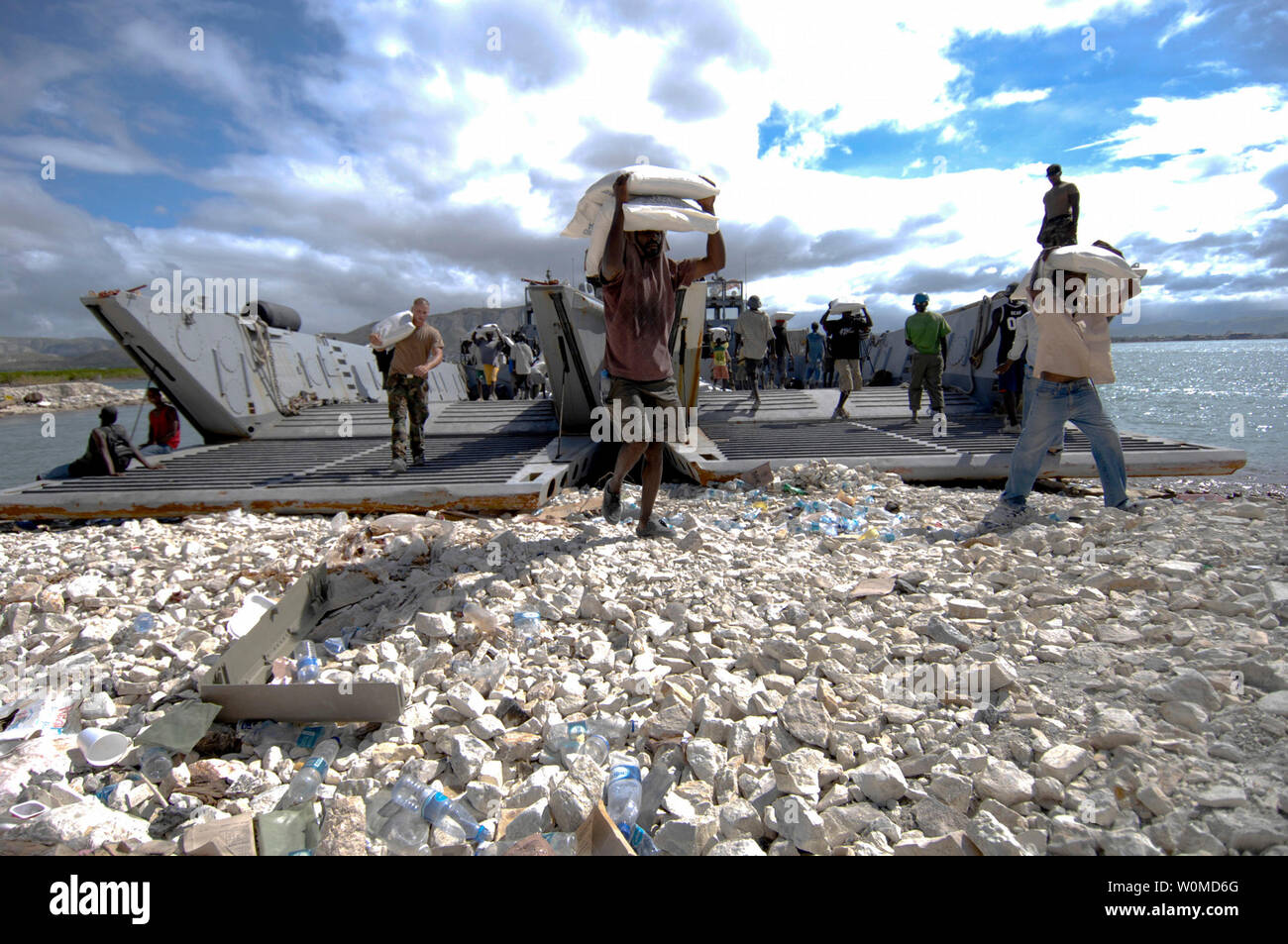 Haitian relief workers assist U.S. military service members, embarked aboard the amphibious assault ship USS Kearsarge, unload food and water to aid those affected by recent hurricanes in Gonaives, Haiti on September 23, 2008.  (UPI Photo/Erik C. Barker/U.S. Navy) Stock Photo