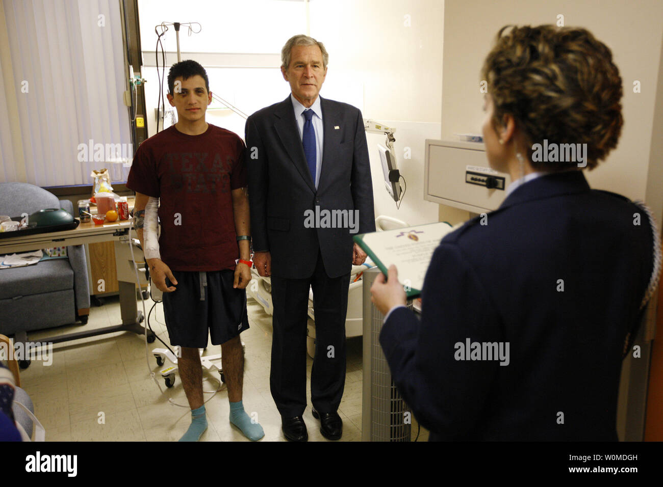 President George W. BushÊstands with U.S. Army Specialist Fernando Aguilar of Tucson, Arizona on December 22, 2008 atÊWalter Reed Army Medical Center in Washington, D.C., as a White House military aide reads Aguilar's Purple Heart citation. Aguilar is recoveringÊfrom injuries sustained when two hand grenades were thrown at his vehicle while on patrol in support ofÊthe war in Iraq.    (UPI Photo/Eric Draper/White House) Stock Photo