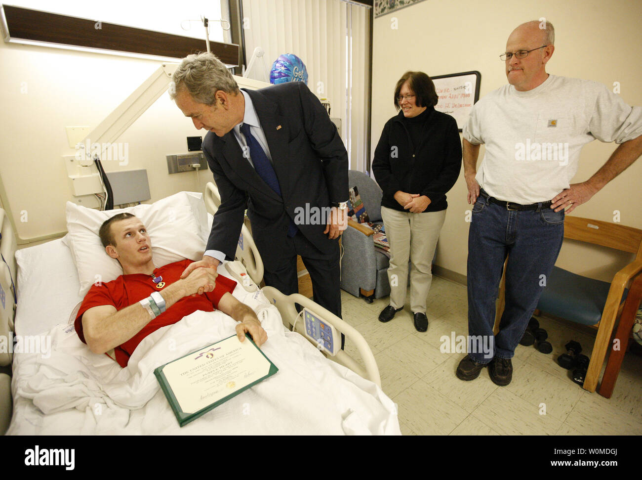 President George W. Bush shakes the hand of U.S. Army PFC Lukas Shook of Strafford, Missouri, after presenting him with a Purple Heart on December 22, 2008, during a visit to Walter Reed Army Medical Center in Washington D.C., where the soldier is recovering from injuries received in the war in Iraq.  Looking on his PFC Shook's mother and father,  Dennis and Cynthia Shook.   (UPI Photo/Eric Draper/White House) Stock Photo