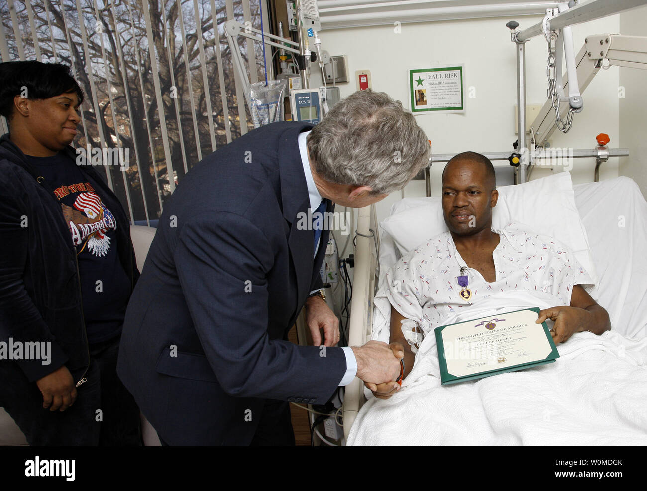 President George W. Bush shakes the hand of U.S. Army Sgt. First Class Neal Boyd of Haynesville, Louisiana, after presenting him a Purple Heart during a visit on December 22, 2008, to  Walter Reed Army Medical Center in Washington D.C., where the soldier is recovering from injuries received in the War in Iraq.  Looking on is SFC Boyd's wife, Joyce.     (UPI Photo/Eric Draper/White House) Stock Photo