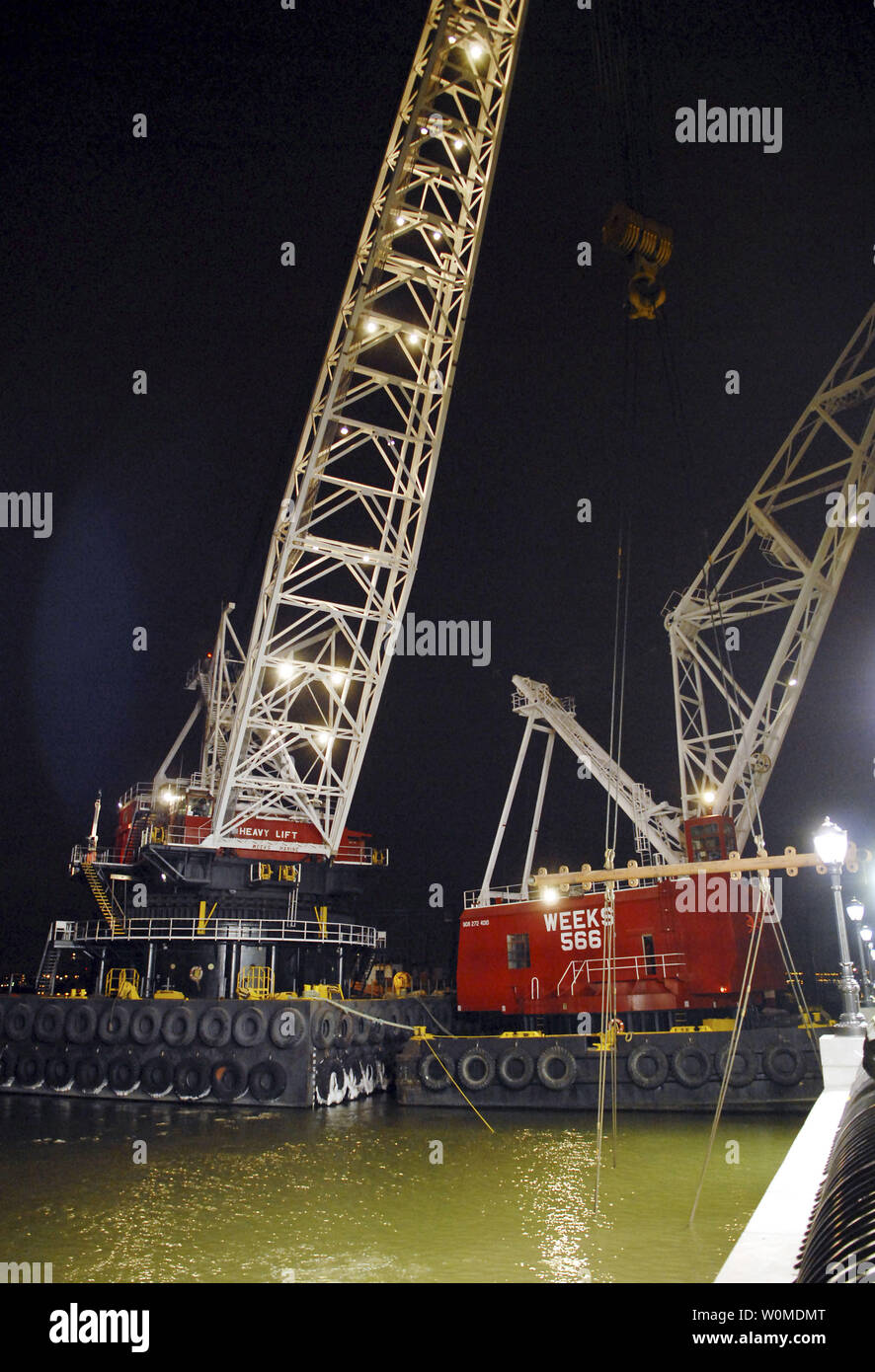 Giant cranes rise into the evening sky above the wreckage of US Airways ...
