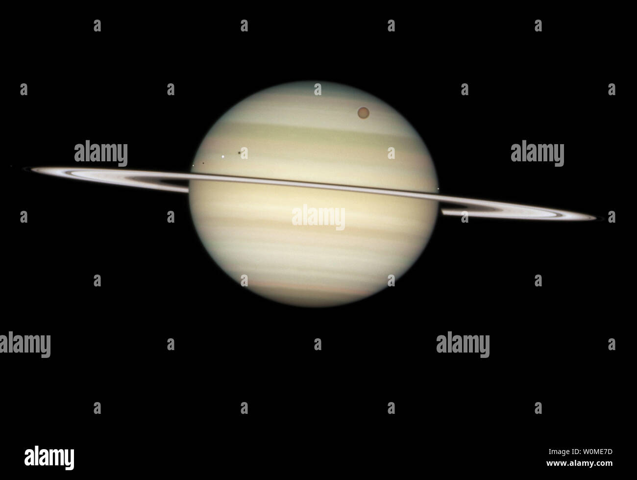 On February 24, 2009, the NASA/ESA Hubble Space Telescope captured a photo sequence of four moons of Saturn passing in front of their parent planet. The moons, from far left to right, are the white icy moons Enceladus and Dione, the large orange moon Titan, and icy Mimas. Due to the angle of the Sun, they are each preceded by their own shadow.   (UPI PHoto/NASA, ESA and the Hubble Heritage Team) Stock Photo