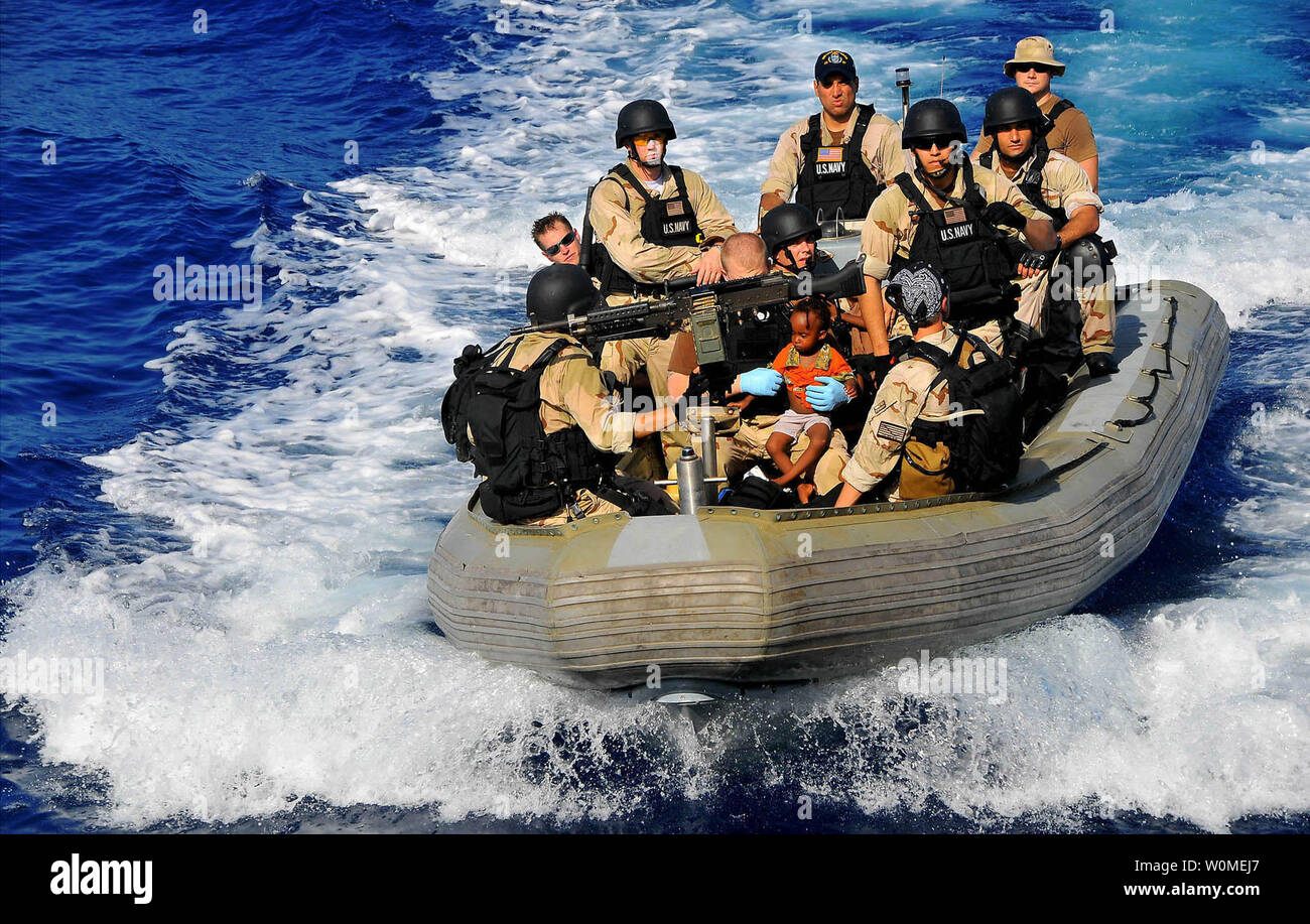 Members of the visit, board, search, and seizure team transport Somali migrant children to the guided-missile cruiser USS Lake Champlain (CG 57) after being rescued from a disabled skiff in the Gulf of Aden on May 24, 2009. The skiff, originally ferrying 52 passengers, was spotted in distress by Lake Champlain helicopter pilots while patrolling the area.   (UPI Photo/Daniel Barker/U.S. Navy) Stock Photo