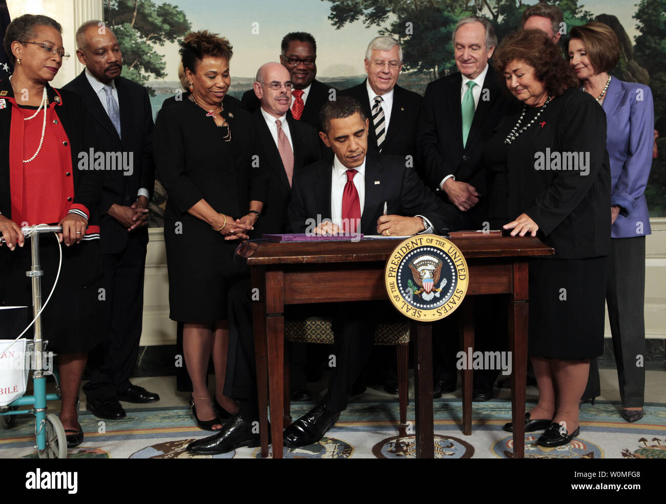 U.S. President Barack Obama, surrounded by members of Congress and Jeanne White-Ginder, mother of Ryan White (2nd R), signs the Ryan White HIV/AIDS treatment extension act of 2009 in the Diplomatic Room of the White House in Washington on October 30, 2009. The act is the largest federally funded program for people living with HIV/AIDS in the U.S. It was named in honor of Ryan White, a  teenager who contracted AIDS through a tainted hemophilia treatment in 1984 and became a well-known advocate for AIDS research and awareness, until his death on April 8, 1990. Stock Photo