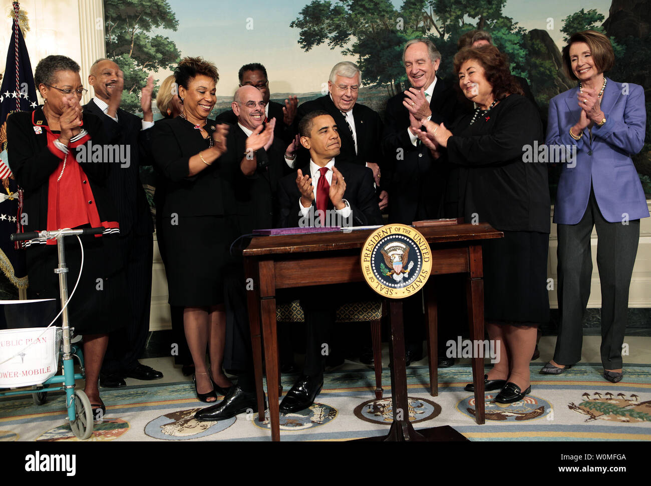 U.S. President Barack Obama, surrounded by members of Congress and Jeanne White-Ginder, mother of Ryan White (2nd R), signs the Ryan White HIV/AIDS treatment extension act of 2009 in the Diplomatic Room of the White House in Washington on October 30, 2009. The act is the largest federally funded program for people living with HIV/AIDS in the U.S. It was named in honor of Ryan White, a  teenager who contracted AIDS through a tainted hemophilia treatment in 1984 and became a well-known advocate for AIDS research and awareness, until his death on April 8, 1990. Stock Photo