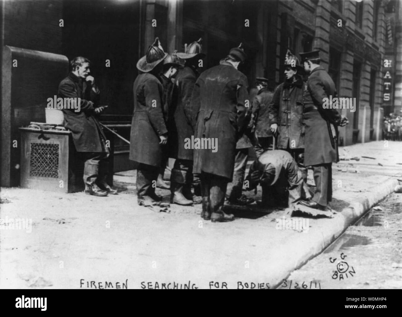 Fire fighters search for bodies which might have fallen through a glass sky light in the sidewalk after the Triangle Shirtwaist Factory fire on March 25, 1911 in New York, New York. March 25, 2011 is the 100th anniversary of the fire when 146 factory workers died after building mangers locked doors leading to all exits. Eye witness accounts by United Press reporter William G. Shepherd along with other reports during the following days and weeks brought the conditions of garment worker into public scrutiny.   UPI/Cornell University Stock Photo