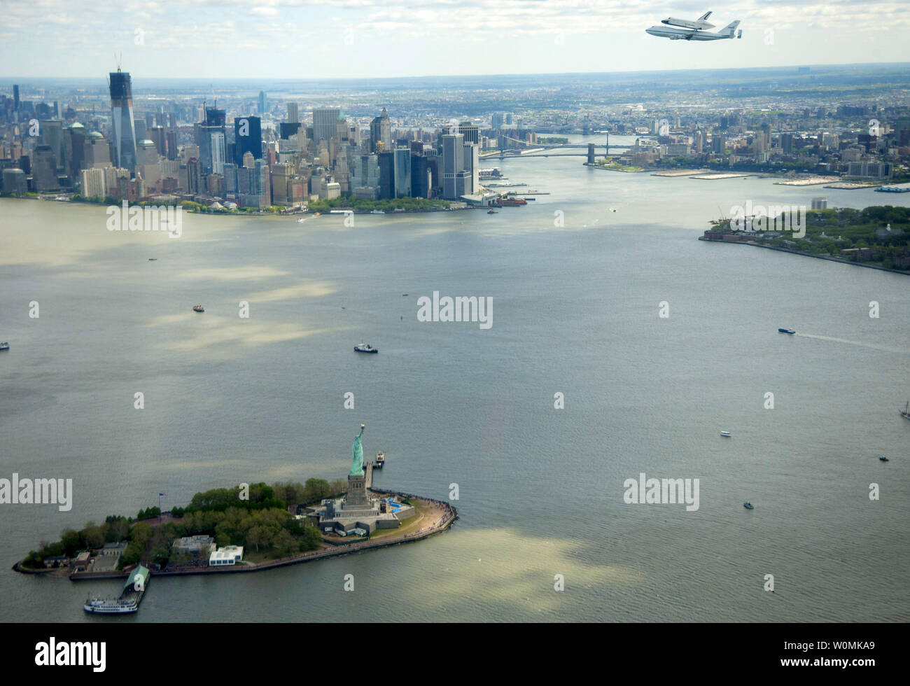 Space shuttle Enterprise, mounted atop a NASA 747 Shuttle Carrier Aircraft (SCA), is seen as it flies over the Statue of Liberty and the lower Manhattan skyline on Friday, April 27, 2012, in New York. Enterprise was the first shuttle orbiter built for NASA performing test flights in the atmosphere and was incapable of spaceflight. Originally housed at the Smithsonian's Steven F. Udvar-Hazy Center, Enterprise will be  placed on a barge that will eventually be moved by tugboat up the Hudson River to the Intrepid Sea, Air & Space Museum in June.    UPI/NASA/Robert Markowitz Stock Photo