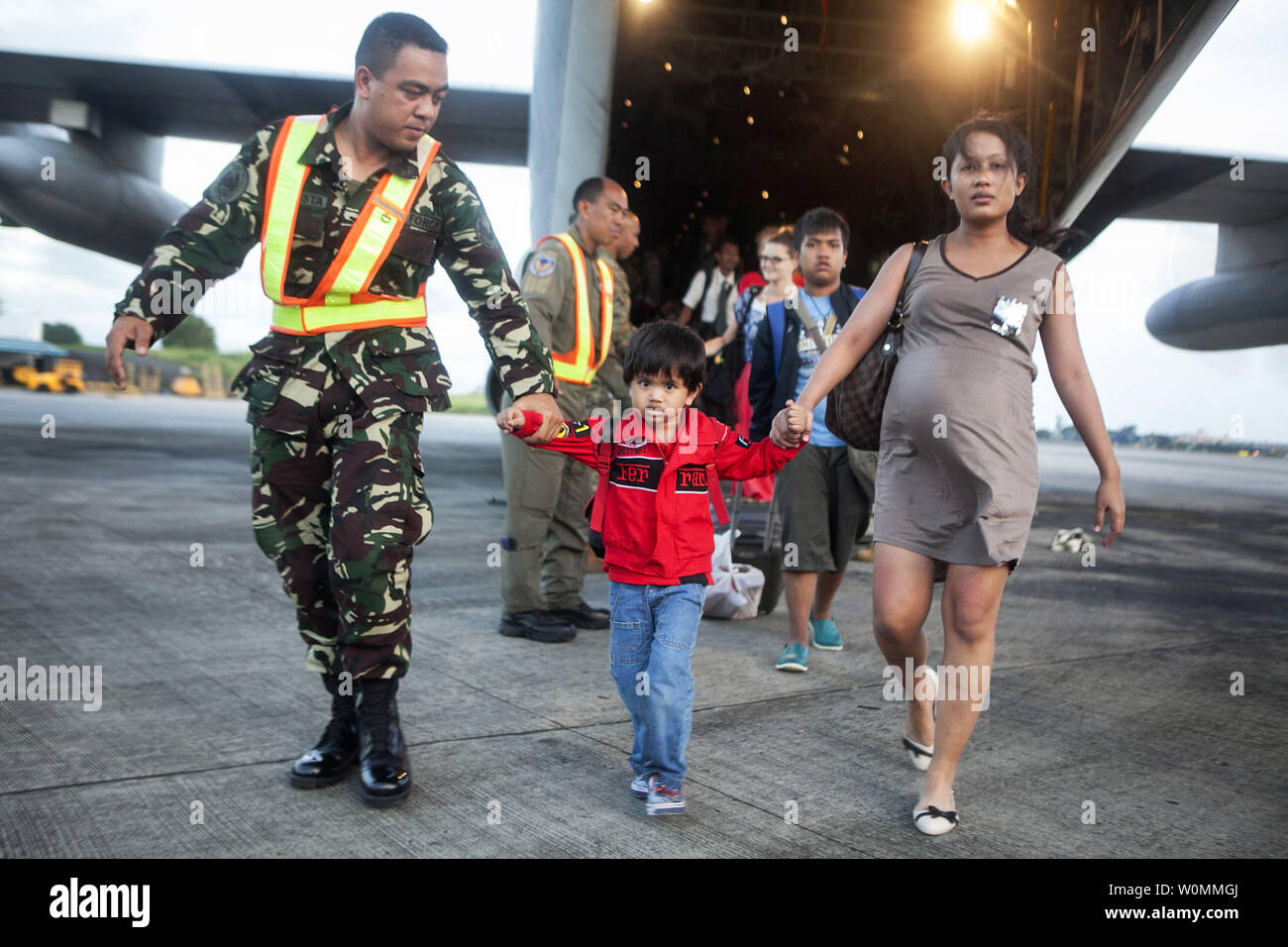 Airman with the Philippine Air Force helps offload Filipino civilians