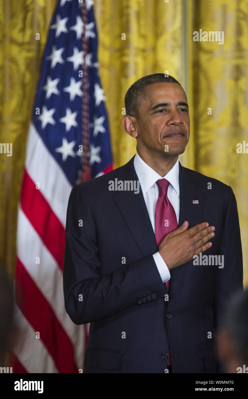 US President Barack Obama listens to the National Anthem before presiding over a naturalization ceremony for active duty service members and civilians in the East Room of the White House in Washington, D.C. on July 4, 2014. The President plans to use executive actions to circumvent congress and move ahead with immigration reform.   UPI/Jim Lo Scalzo Stock Photo