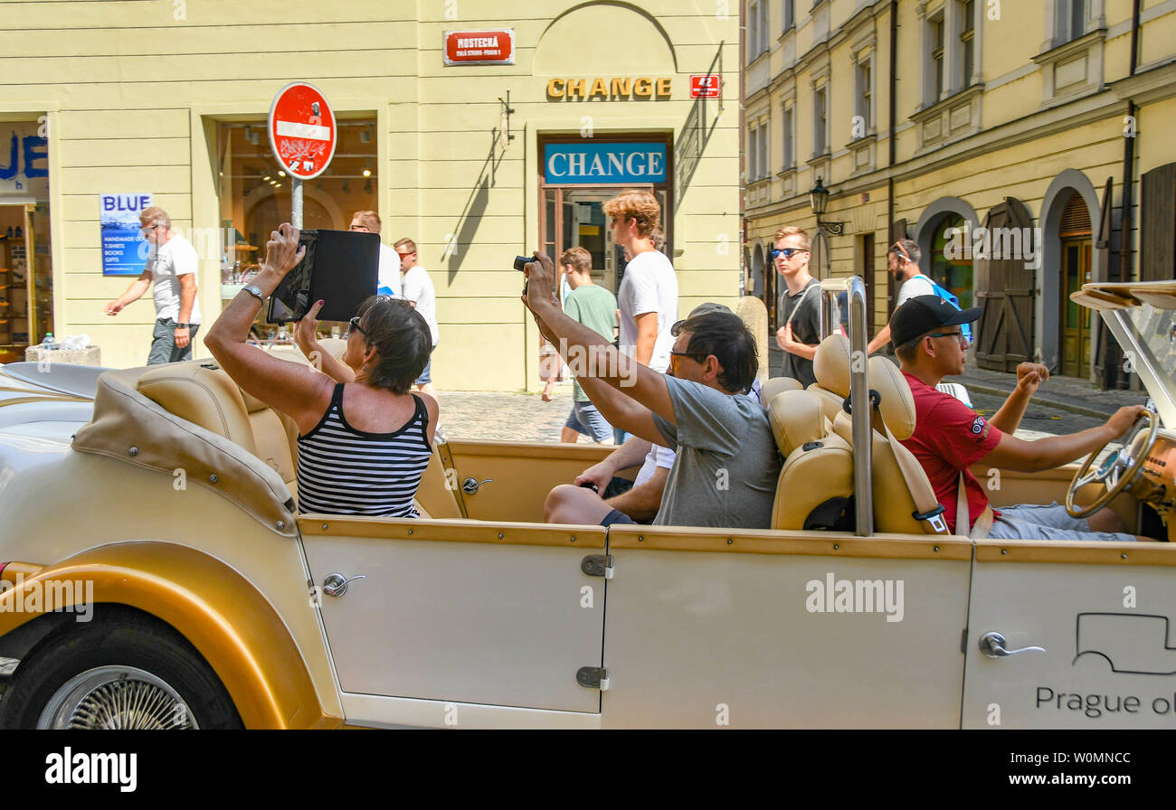 PRAGUE, CZECH REPUBLIC - JULY 2018: People in a replica vintage car taking pictures as they tour the city of Prague Stock Photo