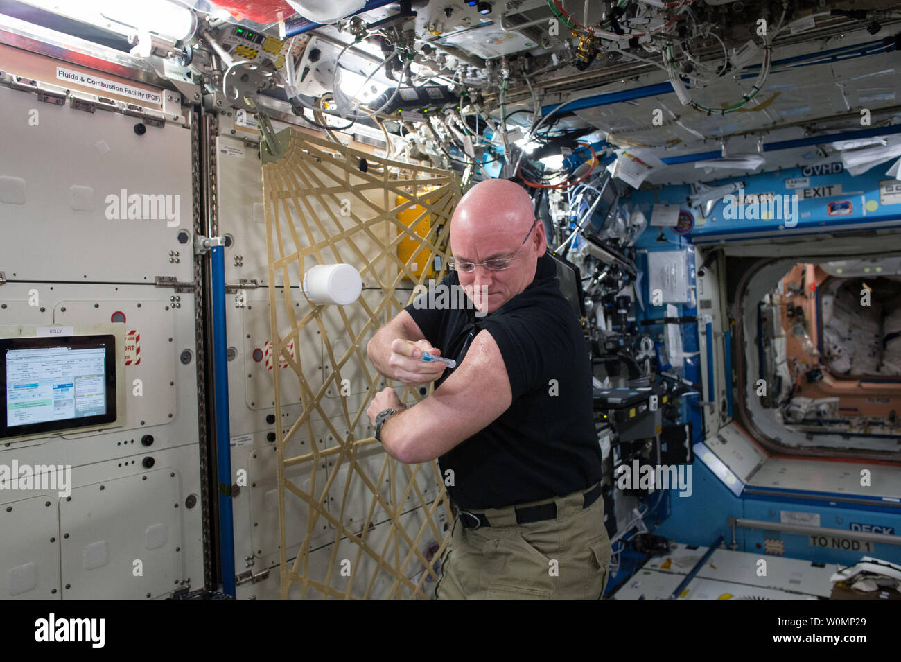 NASA astronaut Scott Kelly gives himself a flu shot on September 24, 2015 for an ongoing study on the human immune system. The vaccination is part of NASA's Twins Study, a compilation of multiple investigations that take advantage of a unique opportunity to study identical twin astronauts Scott and Mark Kelly, while Scott spends a year aboard the International Space Station and Mark remains on Earth. ..Part of NASA's Human Research Program, the One-Year Mission on the International Space Station is a joint effort between the U.S. space agency, the Russian Federal Space Agency (Roscosmos) and t Stock Photo