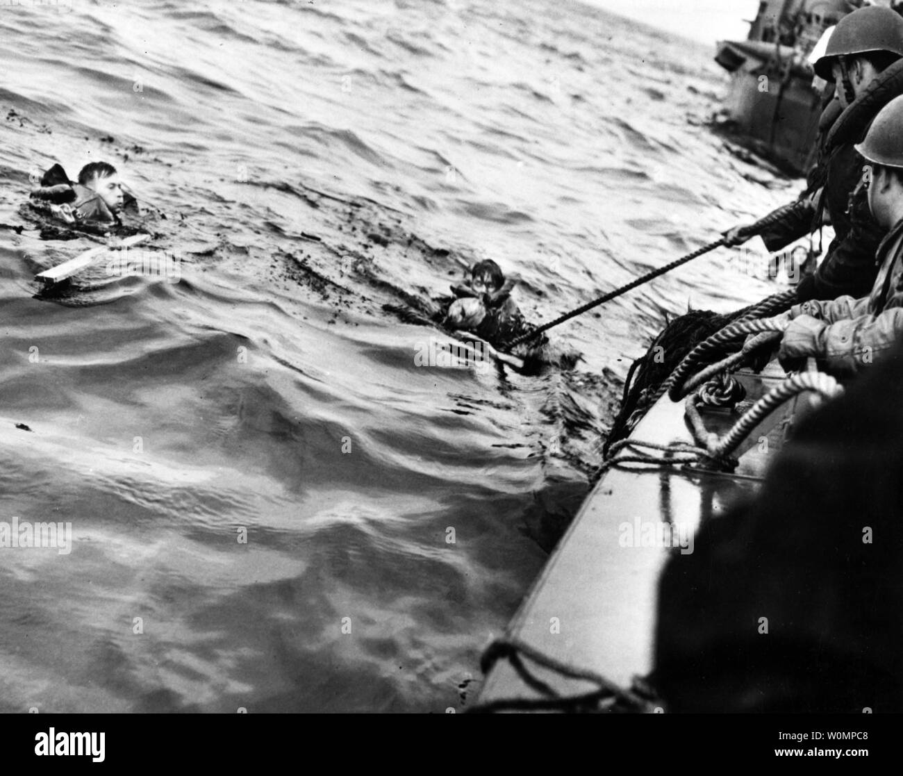 A U.S. Coast Guard boat rescues two survivors from the waters off Normandy, France, after their ship was hit on June 6, 1944, during the Allied invasion of Normandy. The ship ahead of this boat appears to be a minesweeper. Photo by U.S. Coast Guard/National Archives/UPI Stock Photo