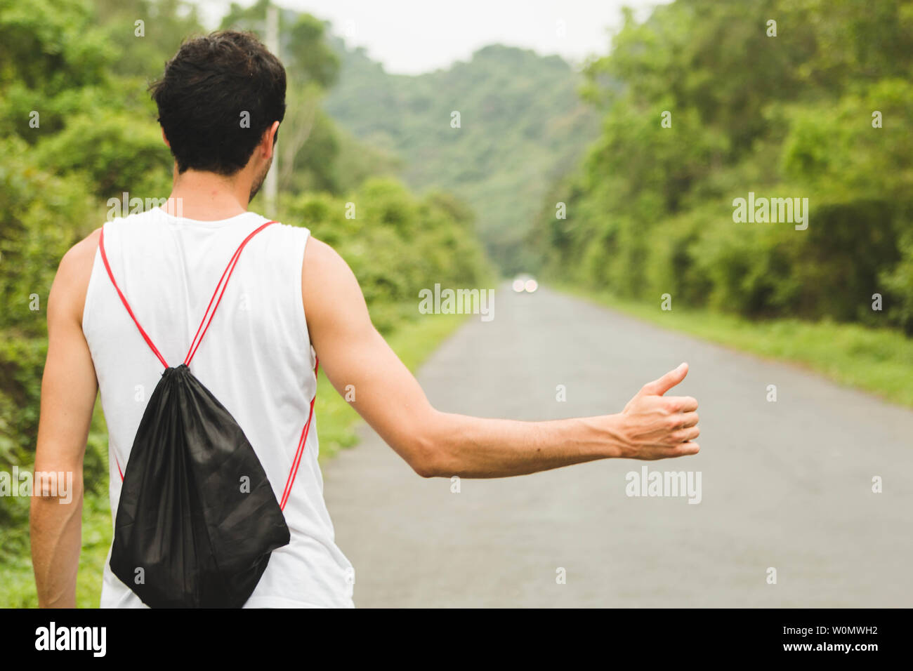 Backpacker tourist hitchhiking on mountain road in Vietnam Stock Photo