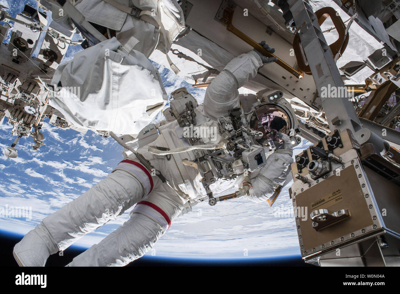 NASA astronaut Drew Feustel seemingly hangs off the International Space Station while conducting a spacewalk with fellow NASA astronaut Ricky Arnold (out of frame) on March 29, 2018. Feustel, as are all spacewalkers, was safely tethered at all times to the space station during the six-hour, ten-minute spacewalk. This was the seventh spacewalk of Feustel's career, while Arnold was on his third spacewalk. The two veteran astronauts successfully installed wireless communications antennas on the station's Tranquility module, replaced a camera system on the port truss and removed suspect hoses from Stock Photo