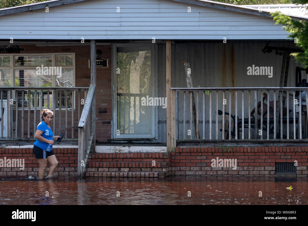 Sylvia Bautista walks to her front doorstep of her flooded home