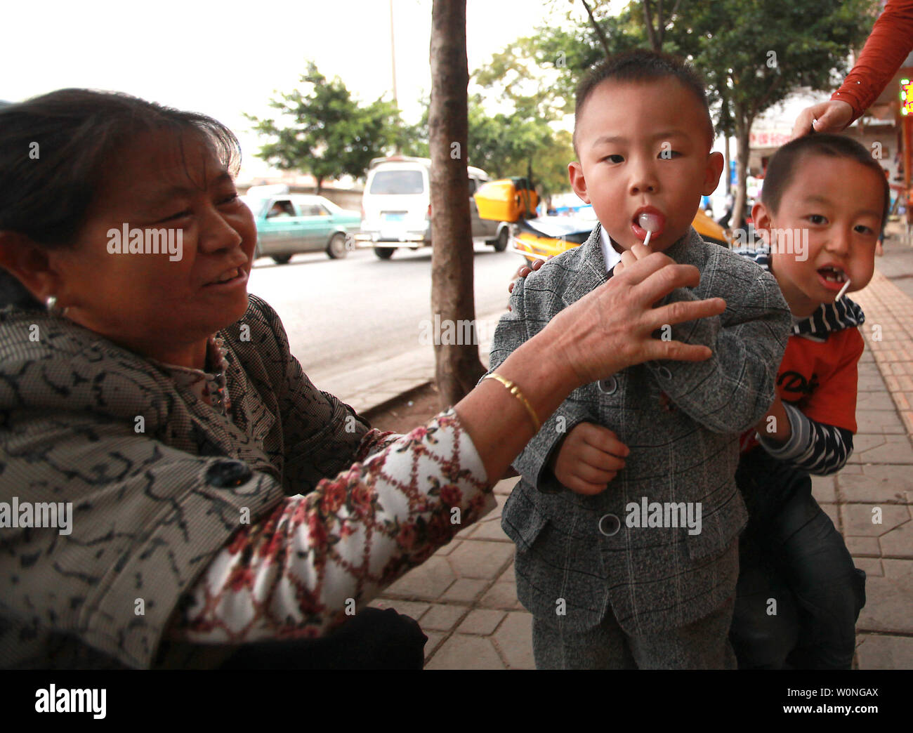 A proud grandmother of two young boys give them lollipops in Kunming, the capital of Yunnan Province, on September 21, 2012.  Due to China's controversial one-child policy and parents preference for having a boy, the country is experiencing a profound skewed sex ration - 120 males born for every 100 females.   UPI/Stephen Shaver Stock Photo