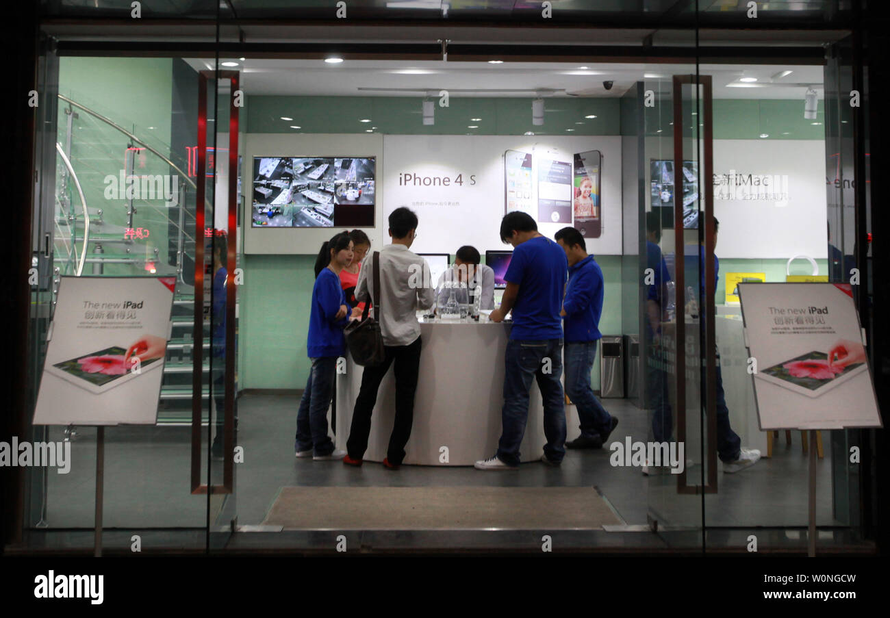 Chinese employees dressed as official Apple staff work at a computer store flagrantly touting itself as an official "Apple Smart Store," selling customers real and 'gray' Apple products in Kunming, the capital of Yunnan Province, on September 24, 2012. Kunming has had several "Apple" stores cease and desist last year do to openly disregarding copyright and trademark infringements. As the case stands, many times a show of force by the government to attack and solve such problems is usually only temporary in order to appease the claimants. UPI/Stephen Shaver Stock Photo