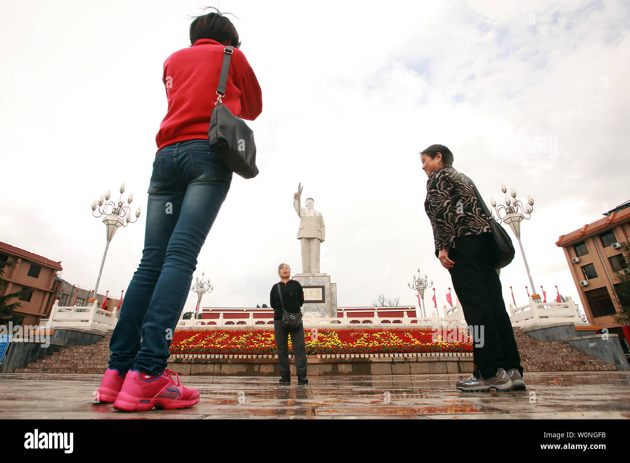 Chinese tourists take pictures in front of one of the few remaining public statutes of the late helmsman Mao Zedong in a square in Lijiang, northern Yunnan Province, on September 29, 2012.    During the Cultural Revolution under the Red Guard, Mao's already glorified image manifested into a personality cult that influenced every aspect of Chinese life, and still persists to across the country.    UPI/Stephen Shaver Stock Photo