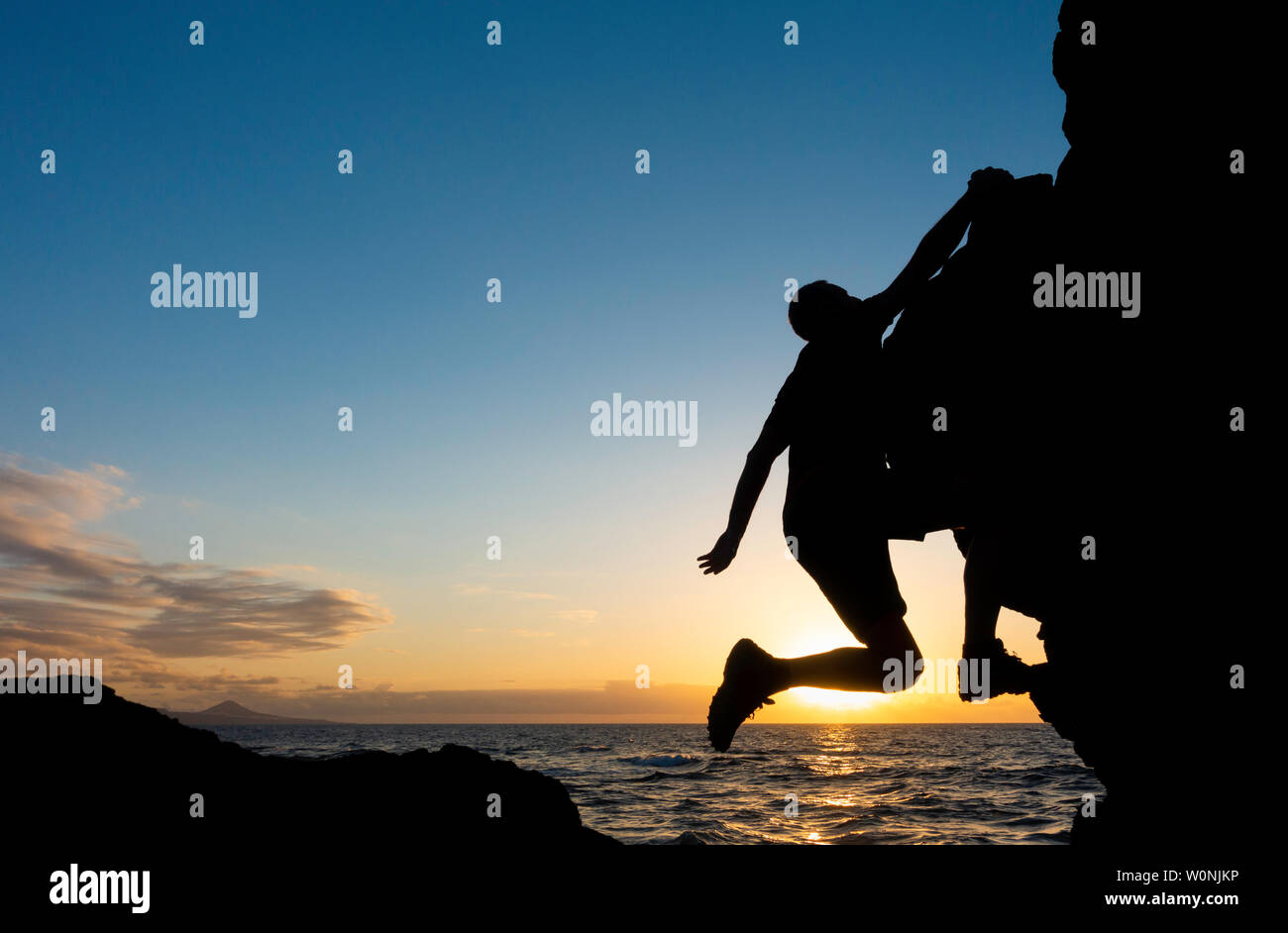 Rock climbing. A climber free climbing (without ropes) on coastal sea