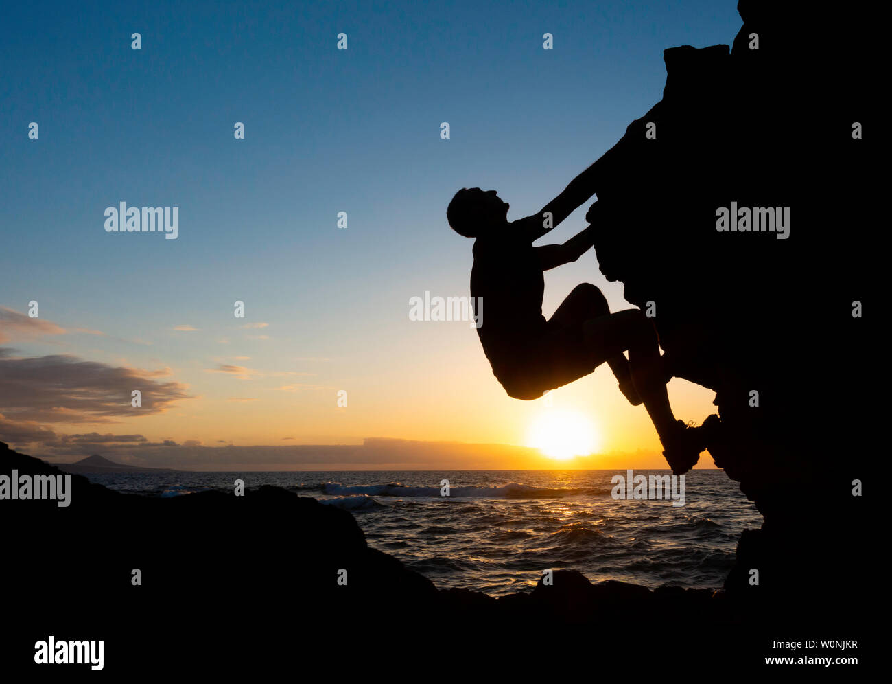 Rock climbing. A climber free climbing (without ropes) on coastal sea