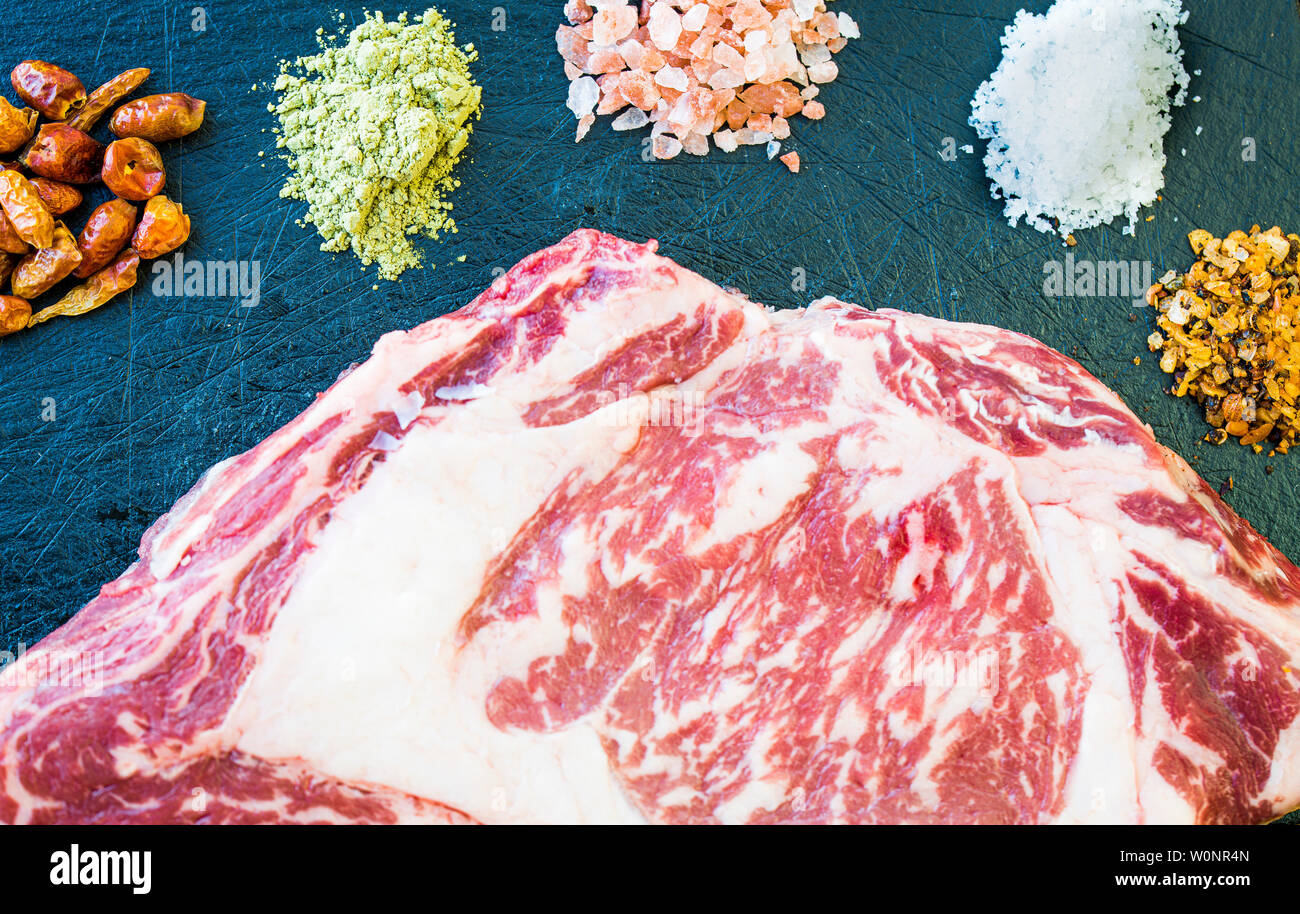 A slice of fresh raw steak, colorful spices  and salt Stock Photo