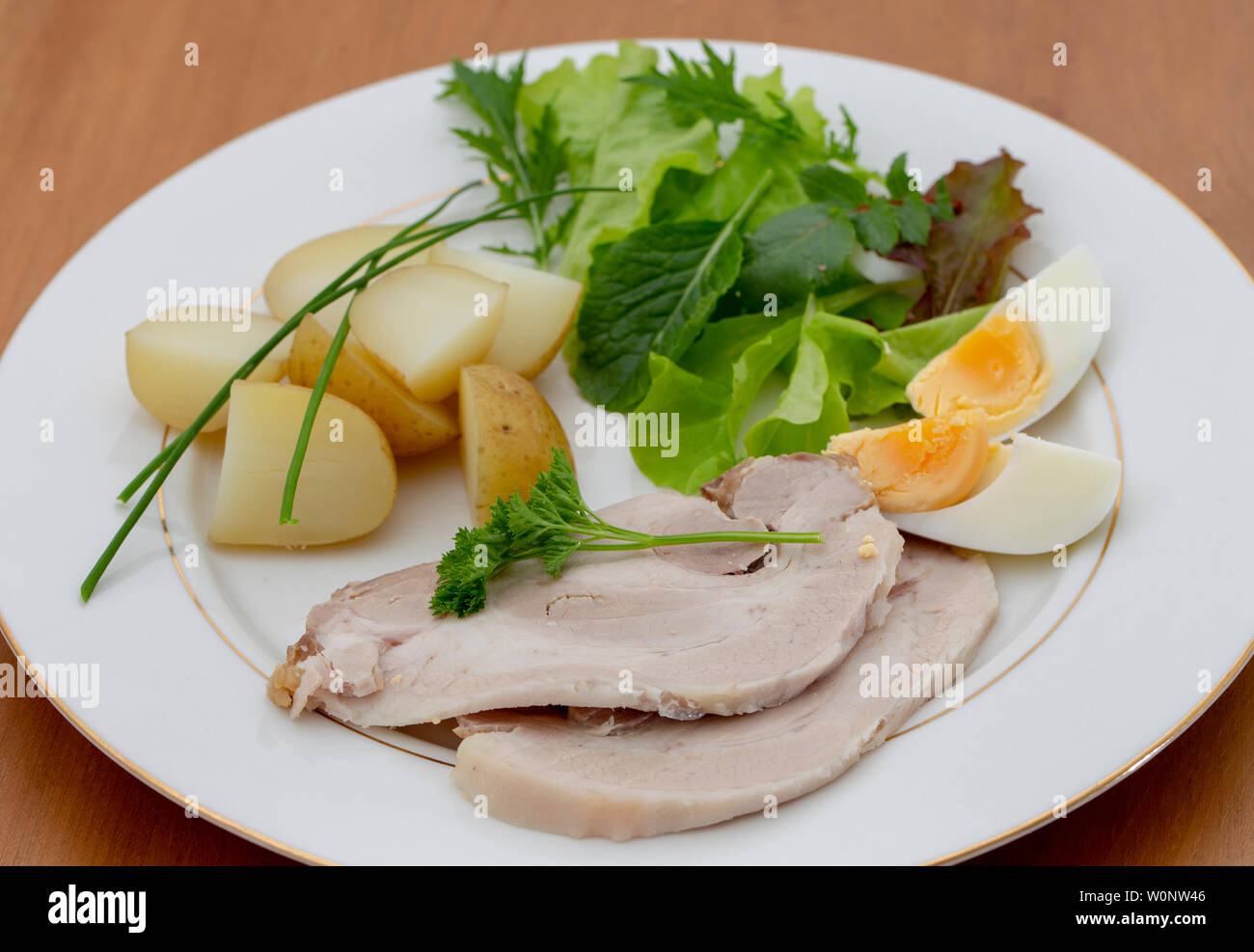 Cold sliced pork dinner with salad, potatoes and boiled egg Stock Photo