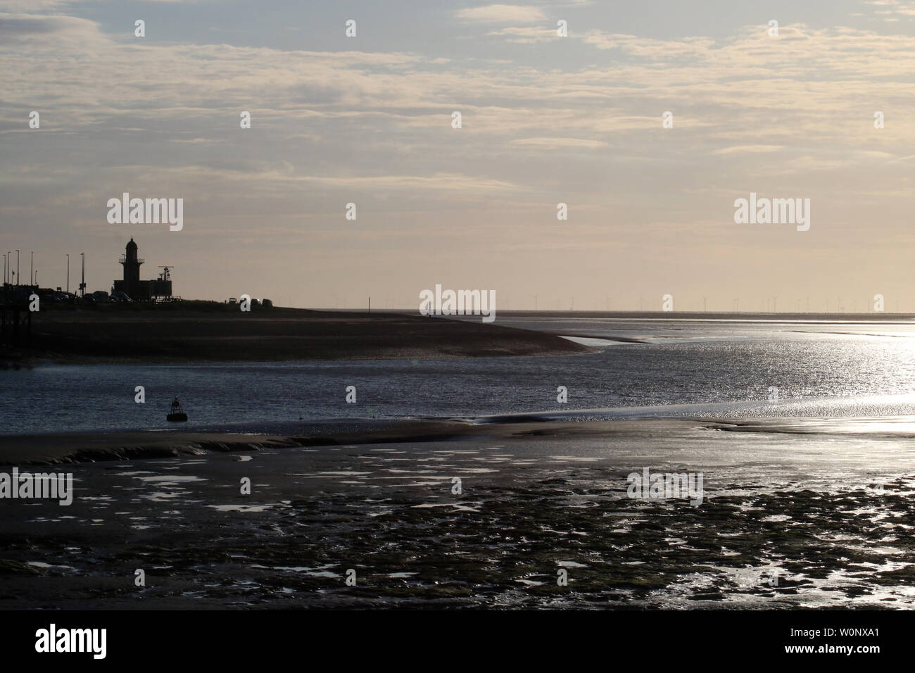 View from Knott End across River Wyre estuary to Fleetwood and to Morecambe Bay with evening light reflecting off water in June, wind farm on horizon. Stock Photo