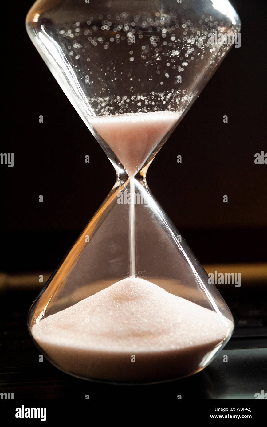An hourglass sits on a laptop computer. Stock Photo