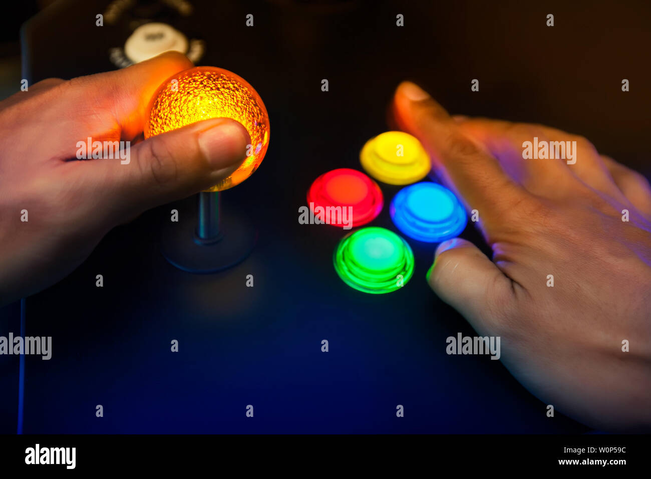 Lighted arcade bubble top joystick and buttons being played by retro gamer. Stock Photo
