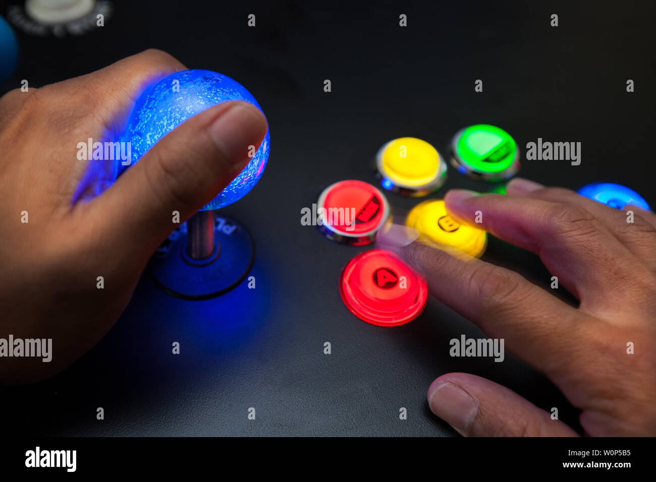 Arcade gamer using a lighted joystick and fighter button layout with neo geo color scheme. Stock Photo