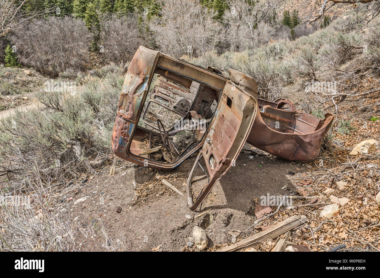 Old, rusted, dilapidated vehicle resting upside down in a rural area still has some glass in the window on the far side.  Pretty amazing since it is r Stock Photo