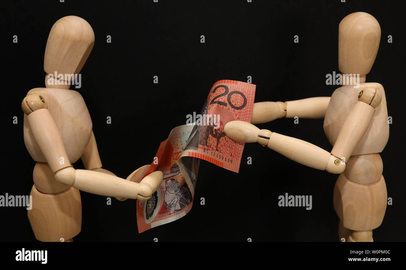 A pair of wooden mannequins talking discussing fighting arguing over financial strain pressure hardship. Struggling over a twenty dollar note. Domesti Stock Photo