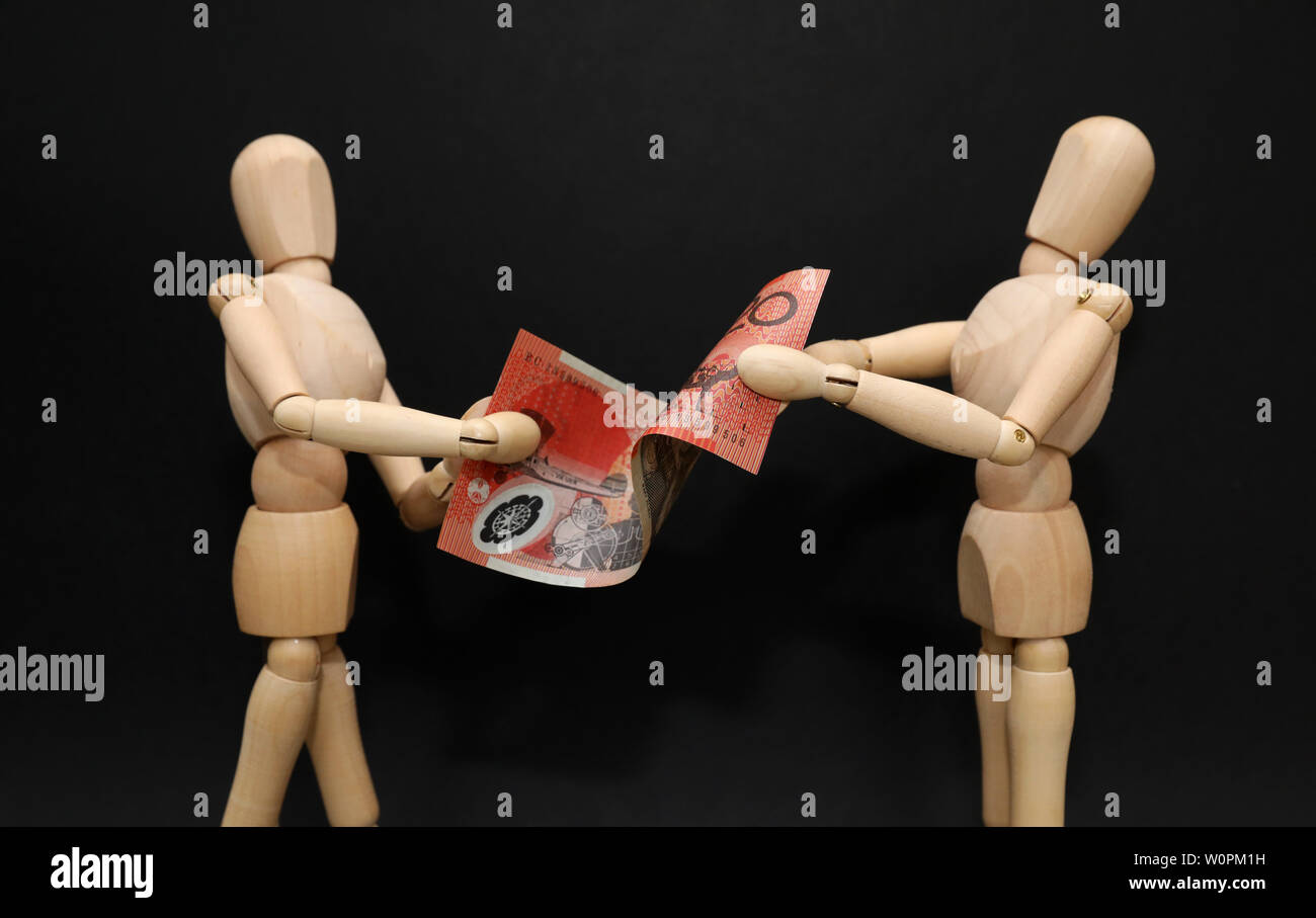 A pair of wooden mannequins talking discussing fighting arguing over financial strain pressure hardship. Struggling over a twenty dollar note. Domesti Stock Photo