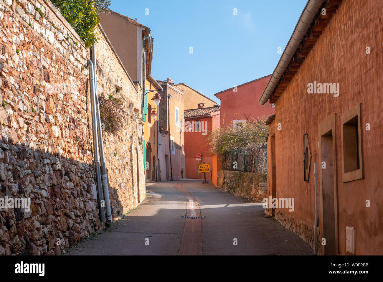 Roussillon, France - January 22, 2019: Houses and buildings facade with the ochre color with clean blue sky as background Stock Photo