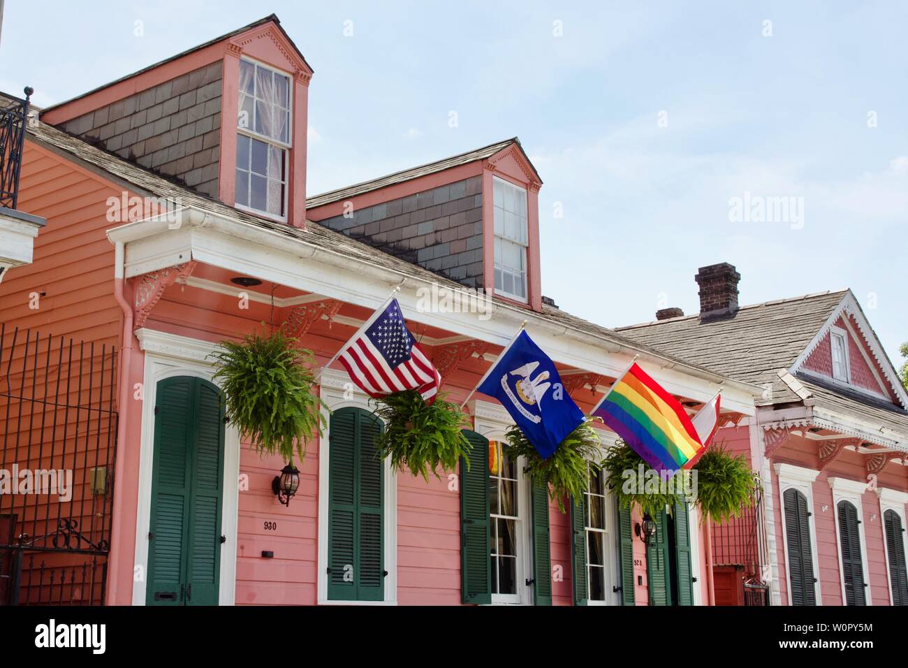 Flags outside of a pink house with green shutters in New Orleans Stock Photo