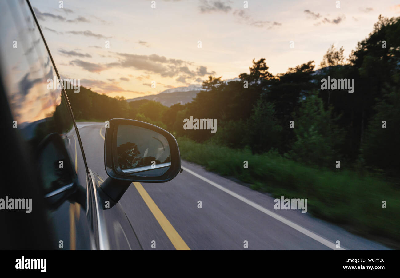 Driving on country road in summer at sunset, side wing mirror view Stock Photo