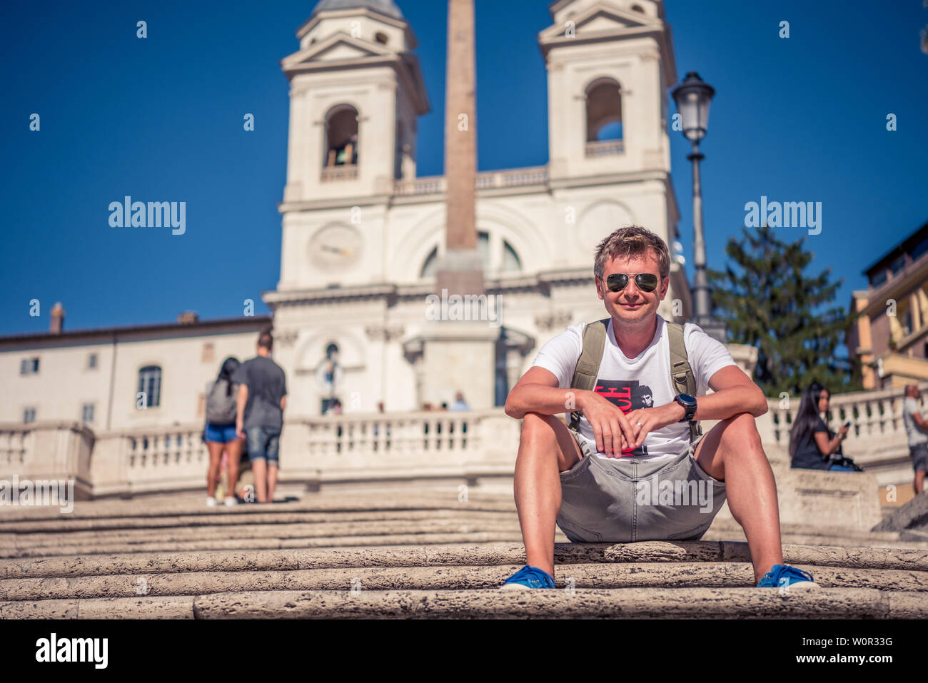 A tourist in the big world. With the backpack, walking equipment, sneakers, a smile on the face and a great deal of knowledge in the soul, the person Stock Photo