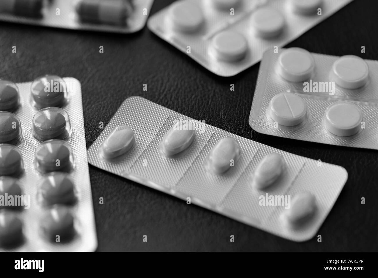 Pills and tablets blisters on a dark background close up black and white Stock Photo