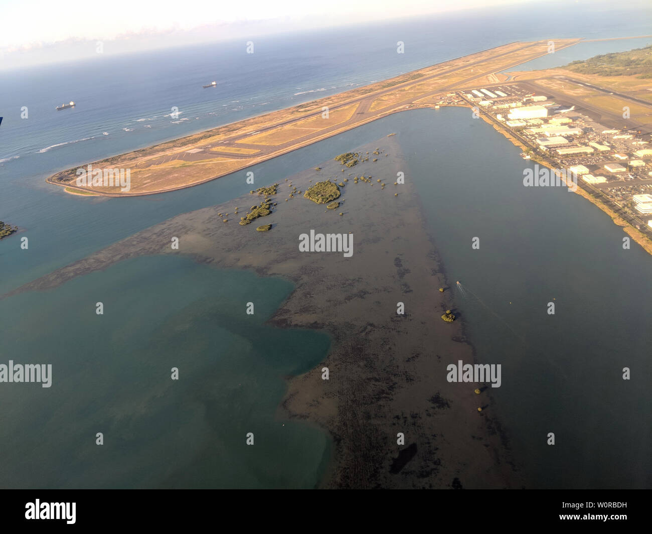 Honolulu - October 25, 2018: Aerial of Airport Reef Runway, planes and Plane hangers at Honolulu International Airport during the day with boats on th Stock Photo