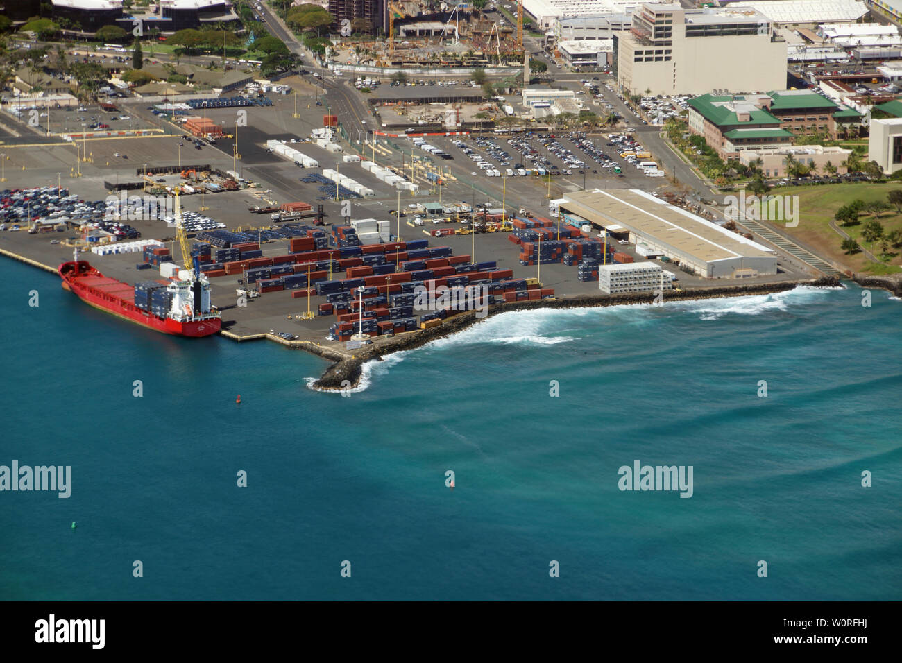 Honolulu - June 26, 2015:  Aerial of Cargo Boat being unloaded on Pier 1, Re-Use Hawaii, Medical College, and Water Treatment Plant along the coast at Stock Photo