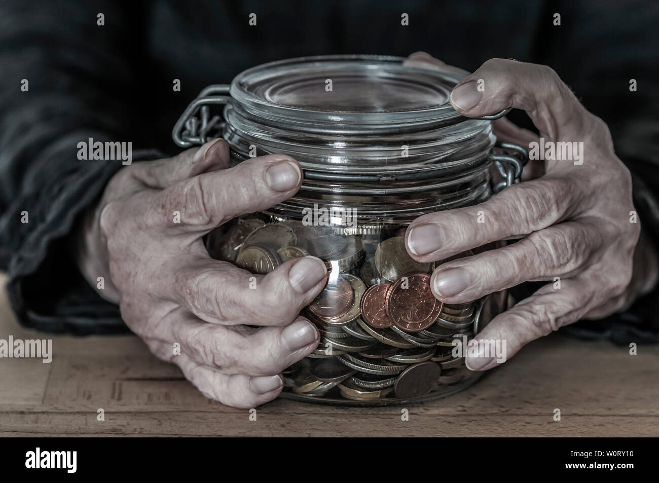 Haende einer alten Frau halten ein Einmachglas mit Kleingeld. Stock Photo