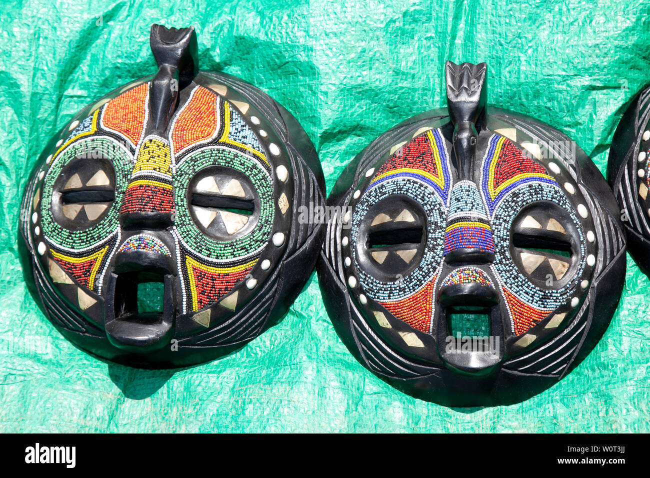 Two round beaded colourful wooden Jamaican Umbaru witch doctors voodoo face masks at Africa Oye, Sefton Park, Liverpool, UK Stock Photo