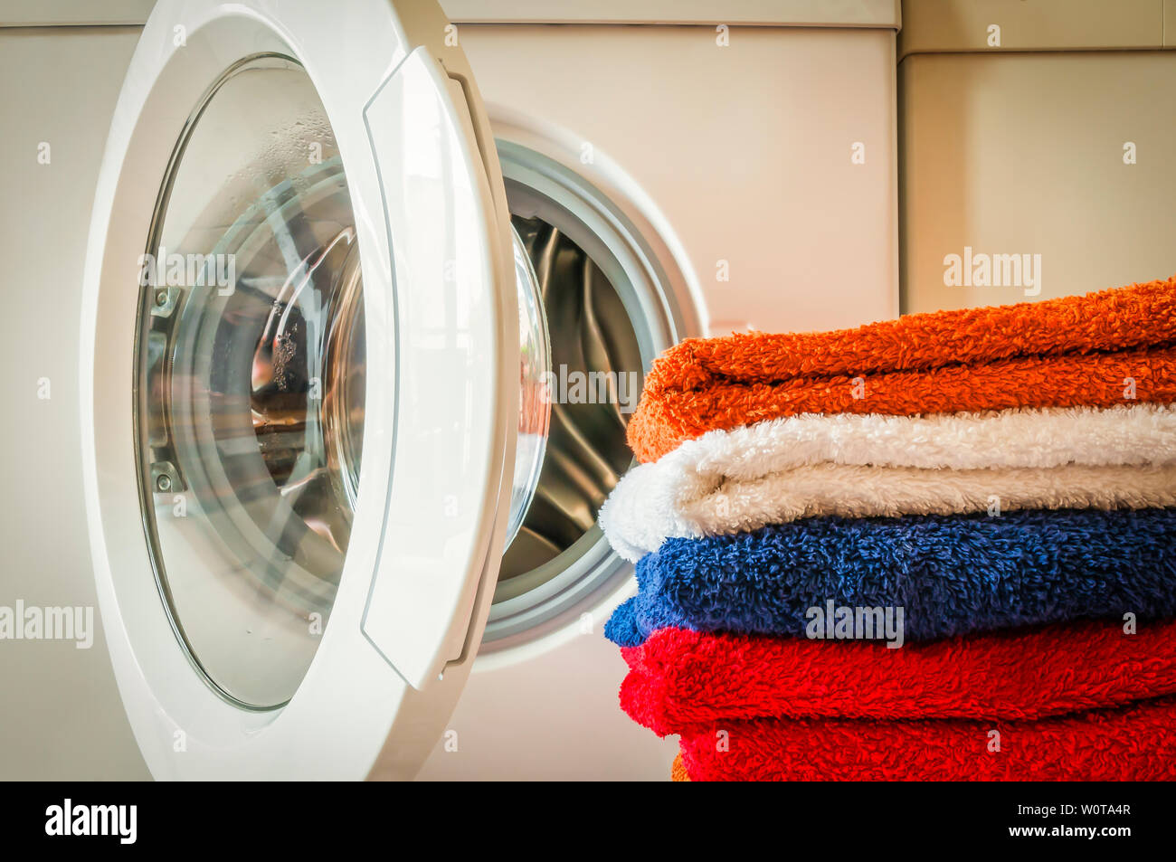 Waschservice, Hausarbeit, Waschmaschine und ein Stapel bunter Handtuecher. Stock Photo