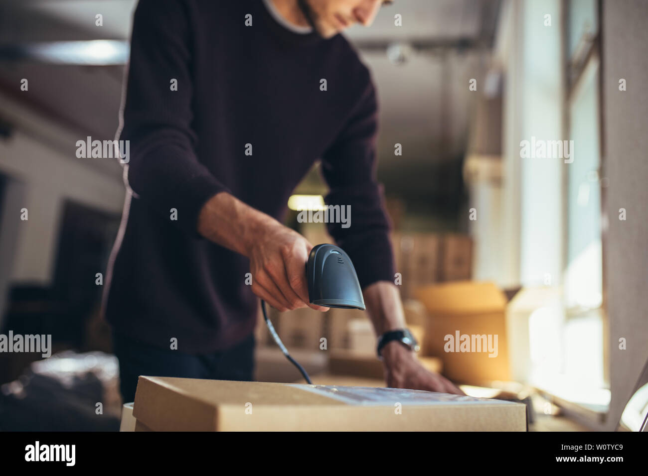 Online seller working at office. Man working on online orders, scanning the parcel before the shipping to the customer. Stock Photo