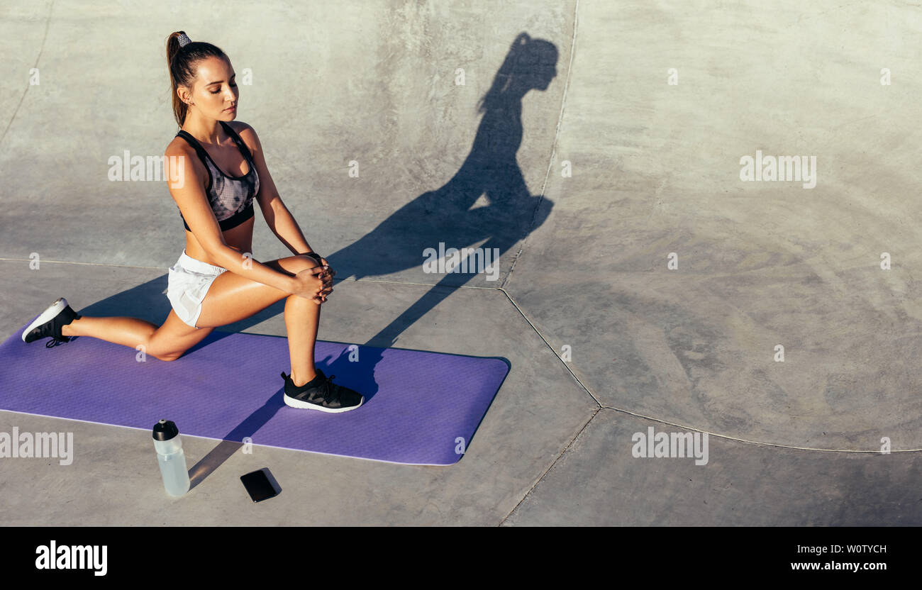 fitness woman stretching in morning. Sporty woman exercising outdoors on fitness mat. Stock Photo