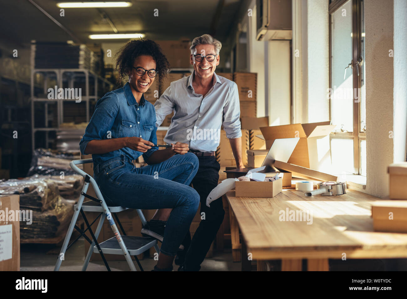 Smiling man and woman at online store warehouse.  Successful drop shipping business partners. Stock Photo