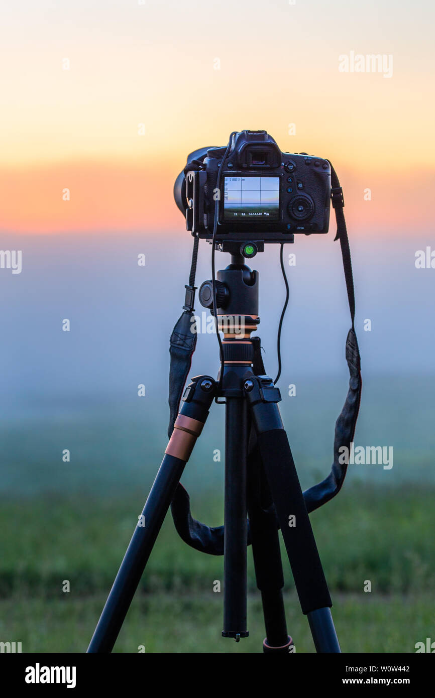 black digital camera on tripod shooting foggy morning landscape at ...