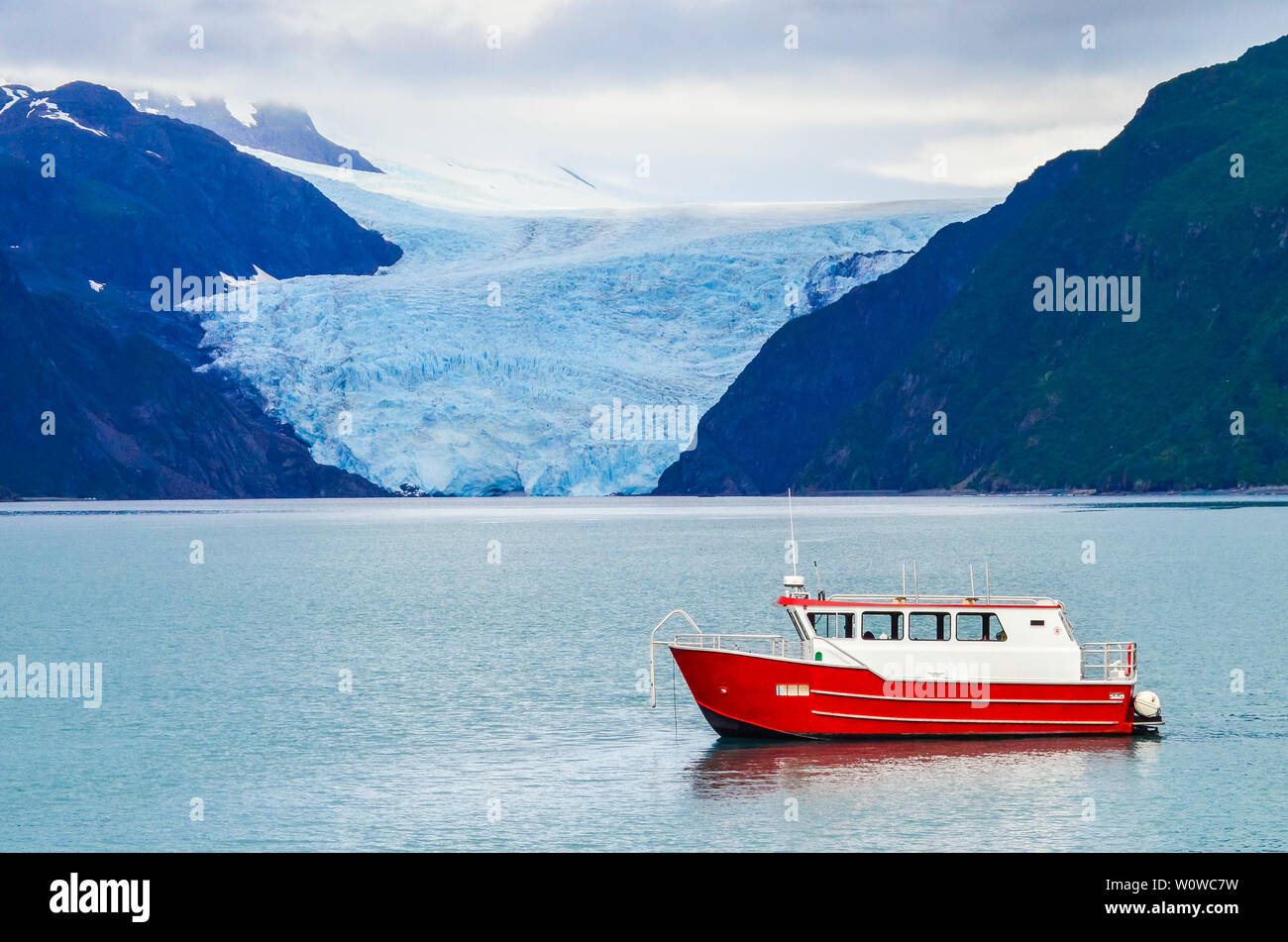 Distant view of a Holgate glacier with red boat in the foreground in Kenai fjords National Park, Seward, Alaska, United States, North America. Stock Photo