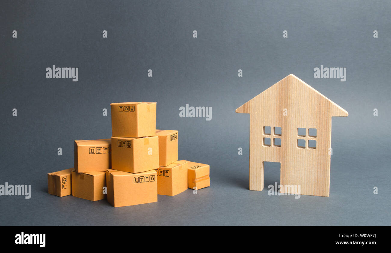 A pile of cardboard boxes and a residential house. Concept of moving to another house or city. beginning of a new stage of life. Property transportati Stock Photo
